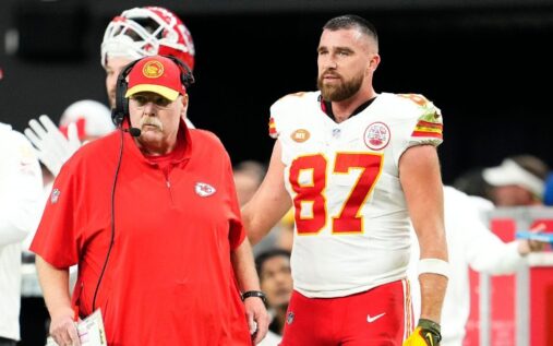 Kansas City Chiefs head coach Andy Reid smiling on the sidelines while wearing a team cap and headset