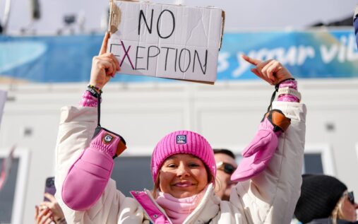 Annika Malacinski holding a protest sign in the snowy stands at the Winter Olympics