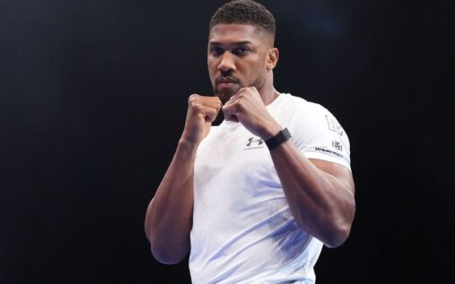 Anthony Joshua looking solemn during a press conference wearing a cap and t-shirt