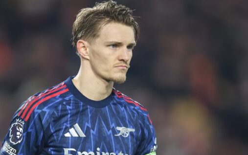 Arsenal captain Martin Odegaard applauding fans on the pitch while wearing the red home kit