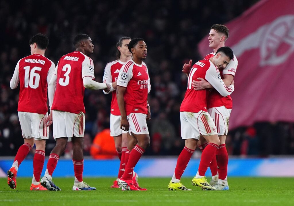 Arsenal players celebrating a goal during a Champions League match under floodlights