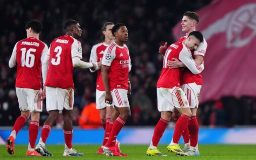 Arsenal players celebrating a goal during a Champions League match under floodlights