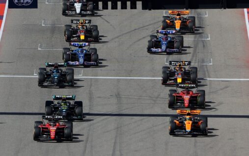 Adrian Newey looking concerned while speaking with Lance and Lawrence Stroll in the Aston Martin garage during F1 testing