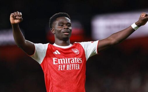 Bukayo Saka clapping to fans while wearing an Arsenal kit during a Premier League match