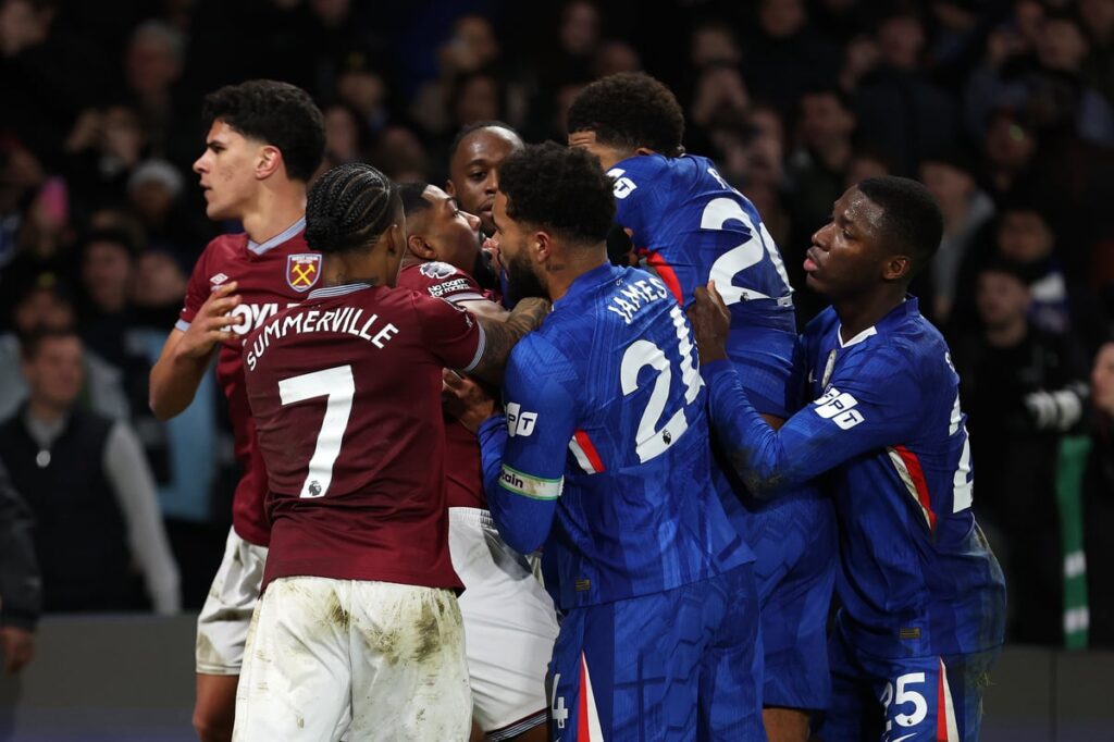 Referee attempting to separate Chelsea and West Ham players during a mass confrontation on the pitch