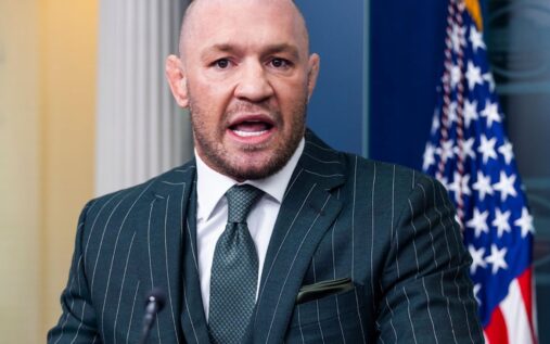 Conor McGregor speaking at a UFC press conference wearing a suit