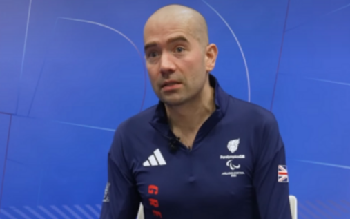 Davy Zyw wearing Team GB winter gear holding a snowboard on a snowy mountain slope