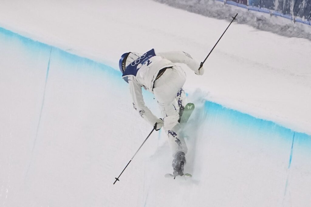 Eileen Gu holding her skis and looking towards the halfpipe course at the Winter Olympics
