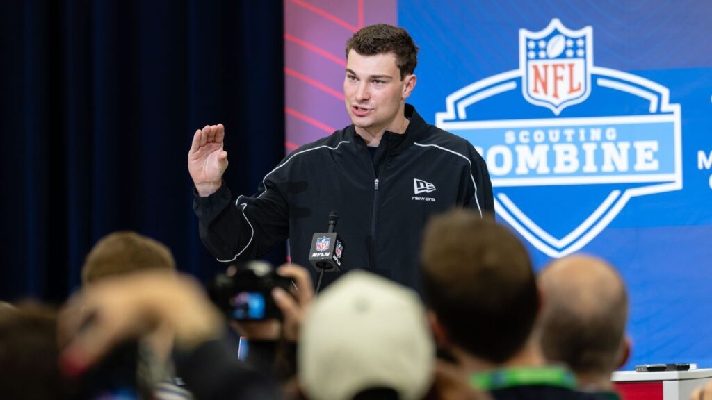 Fernando Mendoza speaking to the media at a podium during the NFL Scouting Combine in Indianapolis