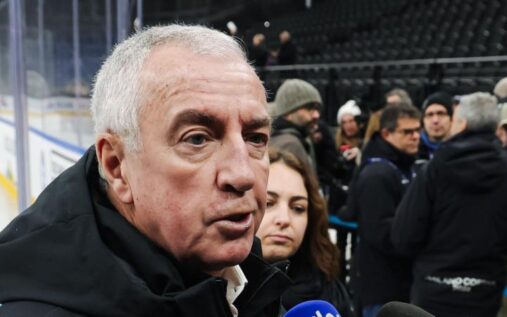 Luc Tardif speaking at a press conference with IIHF branding in the background