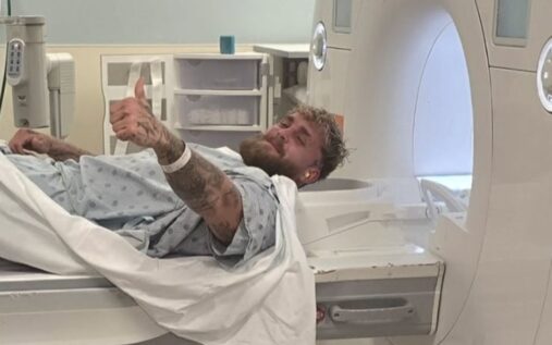 Jake Paul sitting in a hospital bed with a bandaged jaw alongside Jutta Leerdam