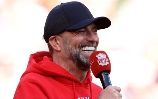 Jurgen Klopp smiling and waving to fans during a Liverpool trophy parade