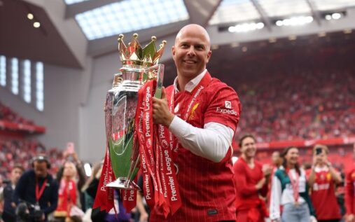 Liverpool players celebrating with the Premier League trophy at a packed Anfield stadium