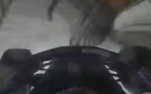 Luke Browning wearing his racing helmet and suit in the paddock area