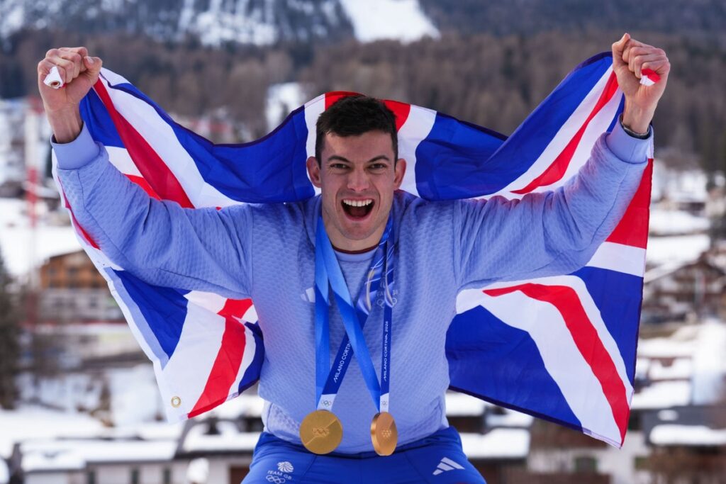 Matt Weston and Charlotte Bankes smiling in Team GB kit holding their gold medals
