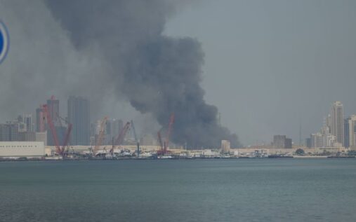 A Formula 1 car driving on the Bahrain International Circuit track at night under floodlights