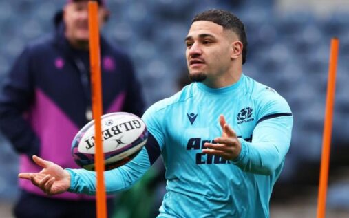 Sione Tuipulotu speaking seriously during a press conference wearing a Scotland rugby training top