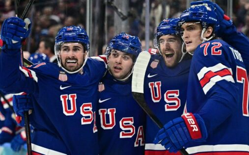 Team USA hockey players celebrating a goal on the ice against Denmark during the Winter Olympics