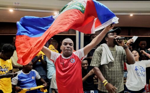 Haiti football fans cheering and waving flags in a stadium crowd