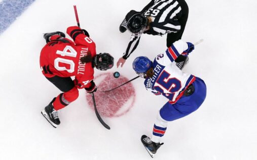 USA and Canada women's hockey players competing for the puck during a previous Olympic matchup