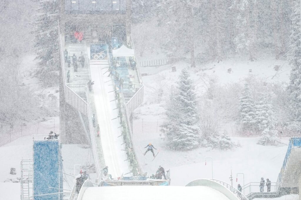 A snow groomer clearing heavy snow from the halfpipe course in Livigno during the Winter Olympics