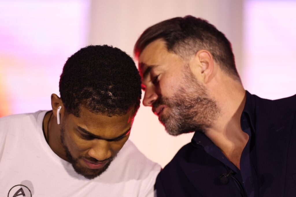 Eddie Hearn standing alongside British heavyweight boxer Anthony Joshua during a ring walk