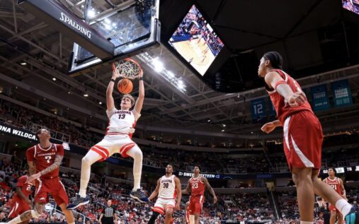 Arizona Wildcats players celebrating their NCAA Sweet 16 victory against the Arkansas Razorbacks on the basketball court.