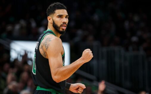 Boston Celtics forward Jayson Tatum warming up on the court in a green jersey