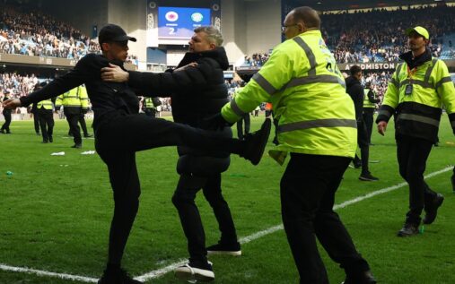 Police officers attempting to control a crowd on the pitch at Ibrox Stadium during the Rangers vs Celtic match