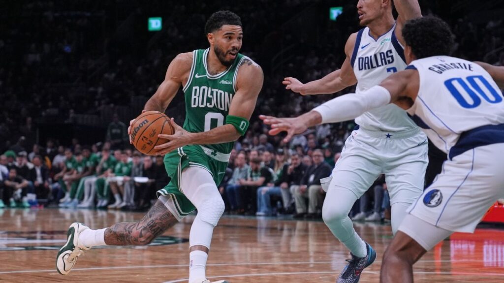 Jayson Tatum driving to the basket in a Celtics jersey during his return game against the Dallas Mavericks