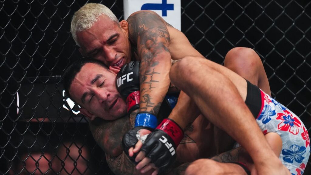 Charles Oliveira grappling against Max Holloway in the octagon during their BMF title fight at UFC 326 in Las Vegas