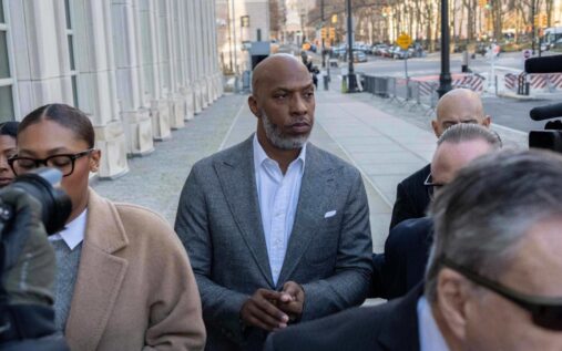 Chauncey Billups wearing a grey suit leaving a federal courthouse surrounded by cameras