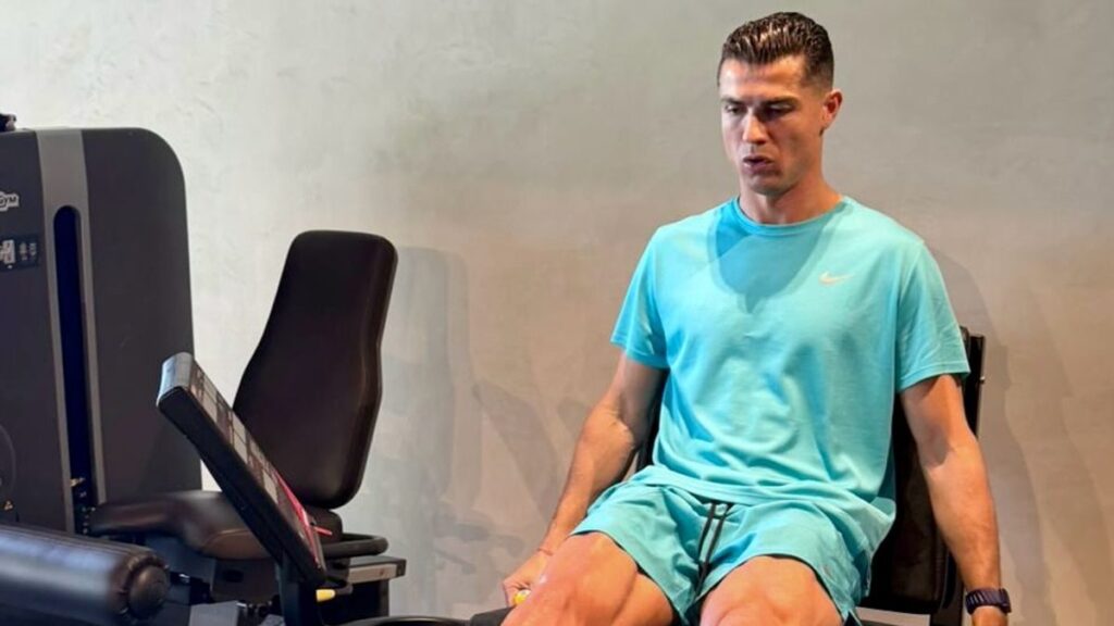 Cristiano Ronaldo wearing a turquoise sports set while working out on a leg press machine in the gym
