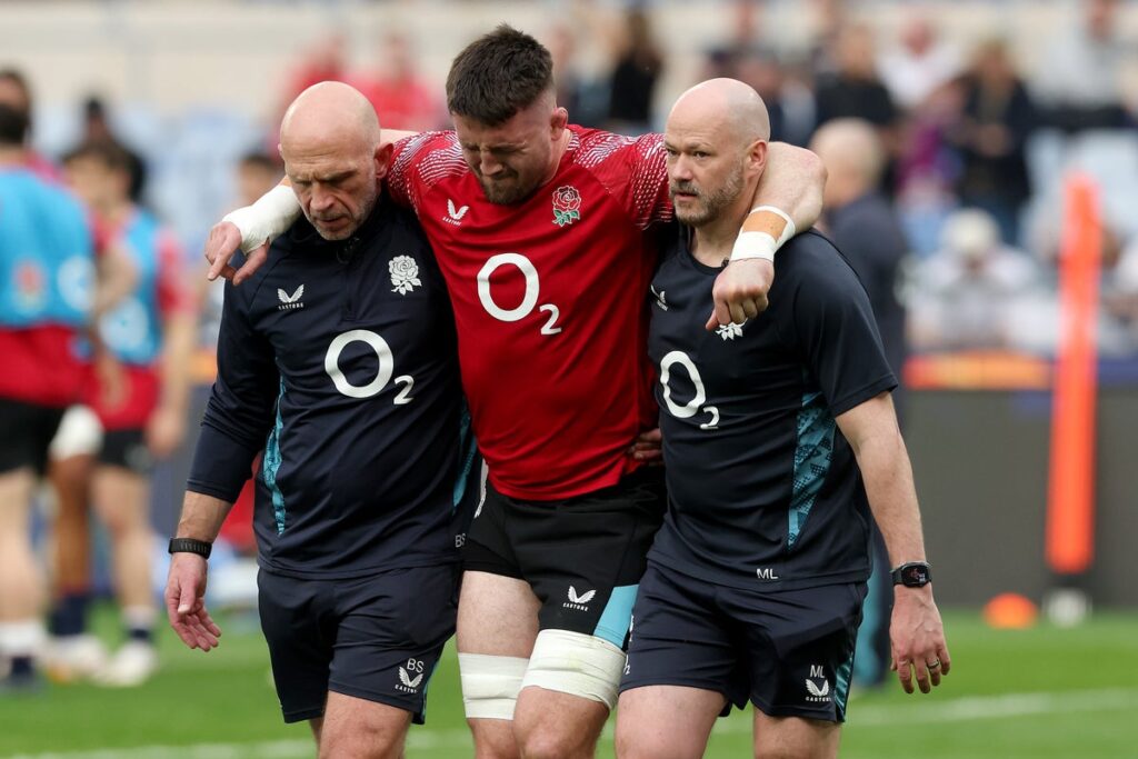 England flanker Tom Curry being helped off the pitch by medical staff during the warm-up
