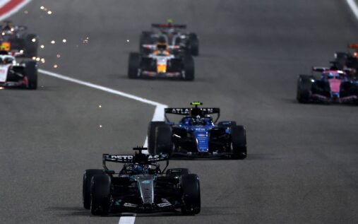 Formula 1 cars racing on a track under floodlights during a Middle Eastern Grand Prix