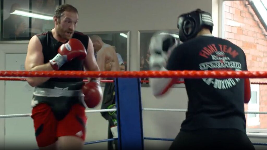 Rico Verhoeven and Tyson Fury wearing headguards during a sparring session in a boxing ring