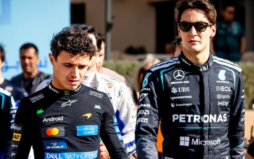 George Russell wearing Mercedes team cap and polo shirt speaking to media in the F1 paddock