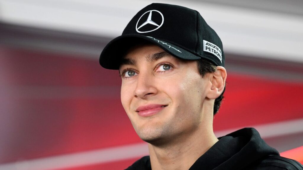 George Russell in Mercedes team apparel speaking to the media in the Formula 1 paddock