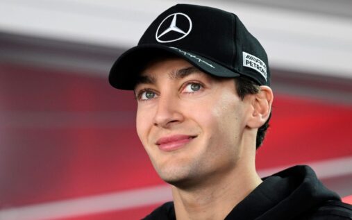 George Russell in Mercedes team apparel speaking to the media in the Formula 1 paddock