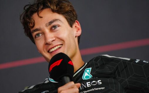 George Russell walking in the paddock wearing Mercedes team kit and sunglasses