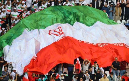 Iran women's football team standing in a line with arms around each other on the pitch in Queensland