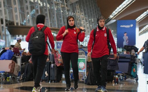 Members of the Iranian women's football team walking with their luggage