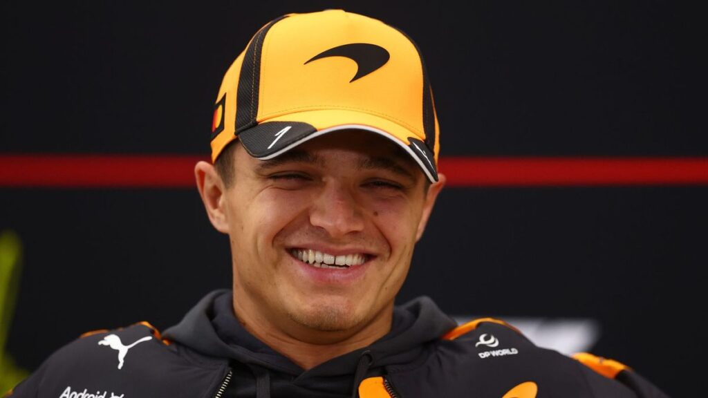 Lando Norris wearing his McLaren race suit and looking determined in the Formula 1 paddock