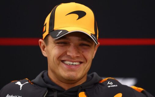 Lando Norris wearing his McLaren race suit and looking determined in the Formula 1 paddock