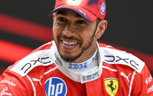 Lewis Hamilton in his red Ferrari race suit smiling confidently during a Formula 1 weekend