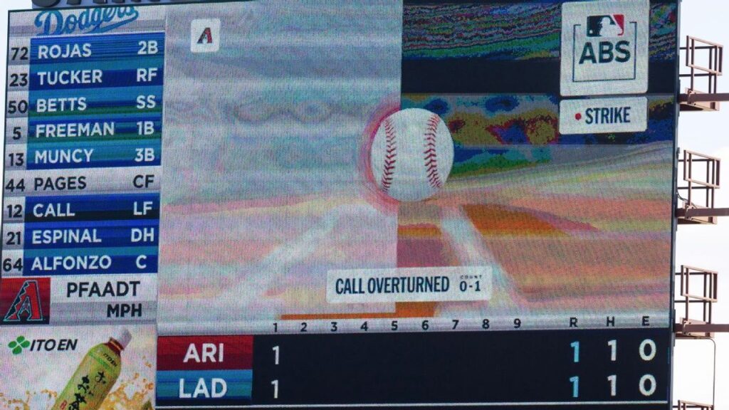 A baseball umpire standing behind a catcher at home plate calling a strike