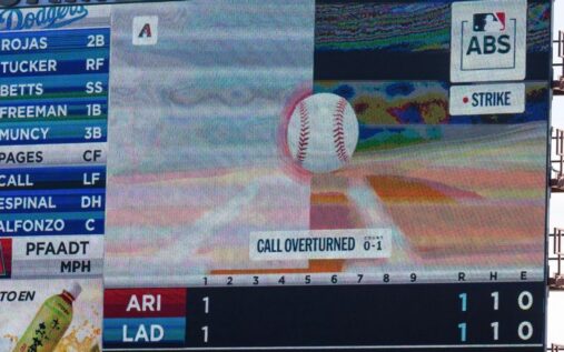 A baseball umpire standing behind a catcher at home plate calling a strike