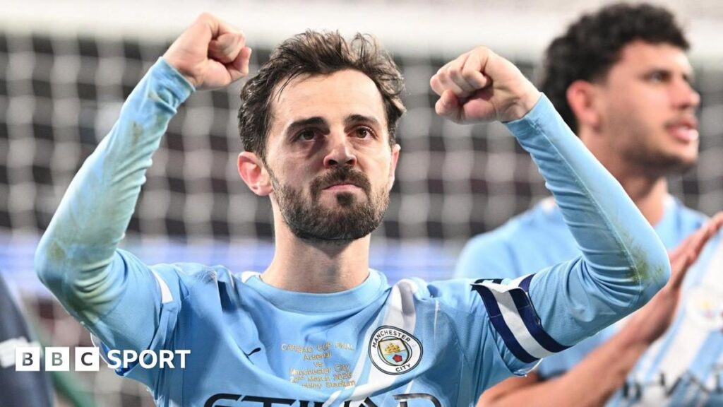 Bernardo Silva holding the Carabao Cup trophy in his Manchester City kit