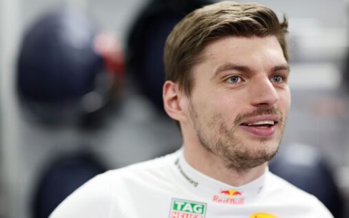 Max Verstappen looking frustrated while wearing his Red Bull Racing team uniform in the Formula 1 paddock