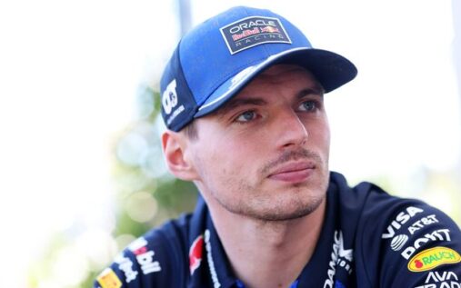 Max Verstappen wearing Red Bull Racing team kit looking pensive in the paddock